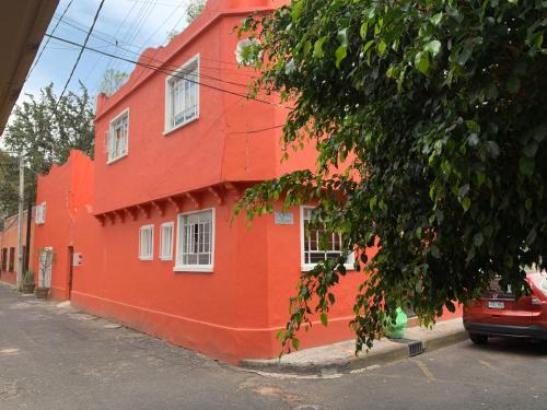 an orange building with white windows on a street at Villa Coyoacan in Mexico City