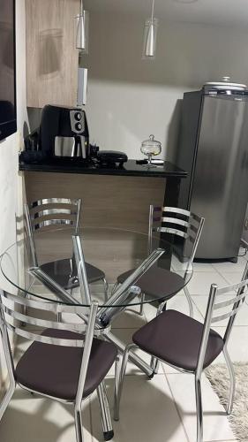 y cocina con mesa de cristal y sillas. en Flat Aldeia Das Águas Village en Barra do Piraí