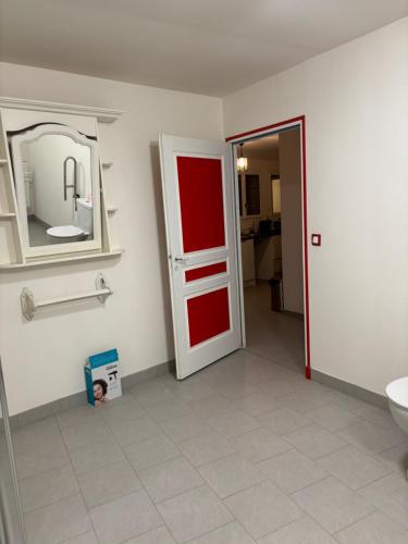 La salle de bains est pourvue d'une porte rouge et d'un miroir. dans l'établissement Gîte Echelle, à Saint-Omer