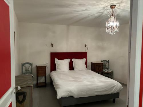 a bedroom with a bed with white sheets and a chandelier at Gîte Echelle in Saint-Omer