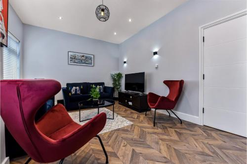 a living room with red chairs and a tv at Welcoming and Radiant - Lovely & Family Friendly! in London