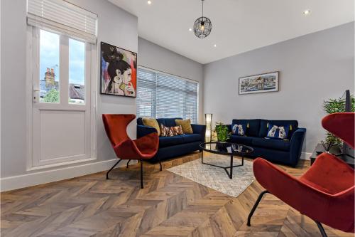 a living room with a blue couch and red chairs at Welcoming and Radiant - Lovely & Family Friendly! in London