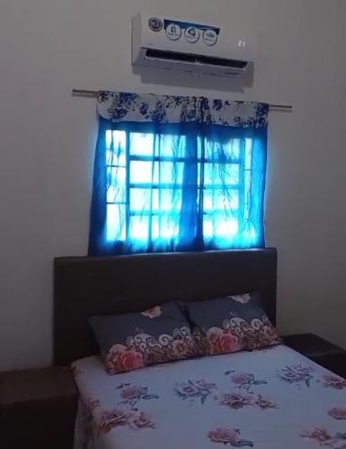 a bedroom with a bed with a blue curtain and a window at Hospedaje 3 DE MAYO in Encarnación