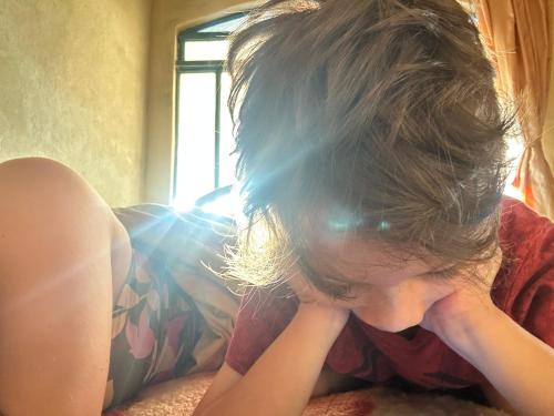 Une petite fille allongée sur un lit avec les mains sur le visage dans l'établissement Damissele, à Betim