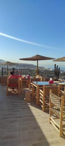 a beach with tables and chairs and an umbrella at SurfAppart Morocco in Tamraght Ouzdar
