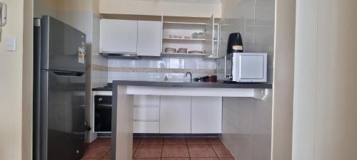 a white kitchen with a sink and a refrigerator at Arriendo departamento La Serena, sector el faro in La Serena