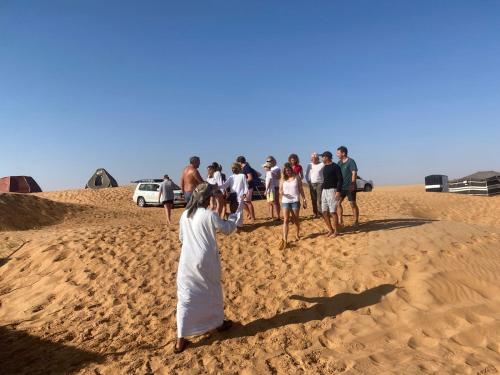 a group of people standing in the sand at Clouds Desert Camp in Bidiyah
