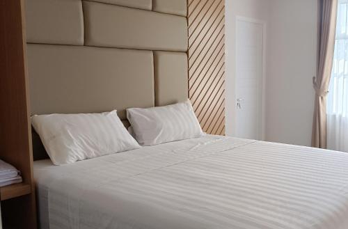 1 cama con sábanas blancas y almohadas en una habitación en D'Ninety Six Inn Hotel Gunungkidul, en Siyonokulon