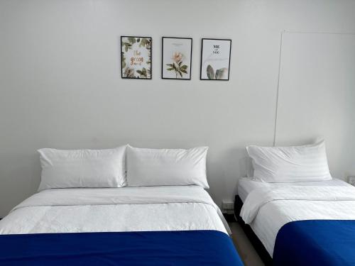 two beds in a bedroom with three pictures on the wall at The Sceneสุพรรณบุรี in Suphan Buri
