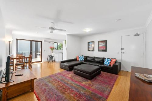 a living room with a black couch and a table at Spacious & Comfy 2 Bed 2 Bath 2 Car - Auchenflower in Brisbane