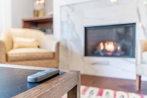 a remote control on a table in a living room with a fireplace at Luxurious & Modern 4BR House w/ 3 Car Parking in Burlington