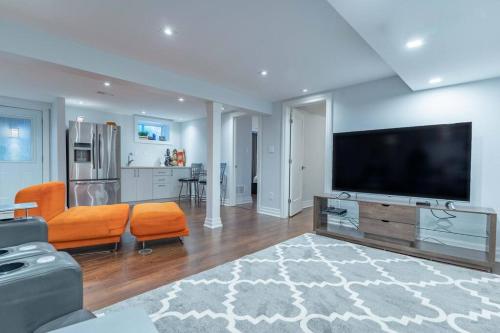 a living room with a flat screen tv and orange chairs at Luxurious & Modern 4BR House w/ 3 Car Parking in Burlington