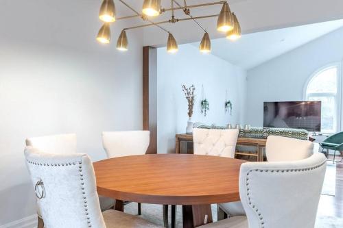 a dining room with a wooden table and white chairs at Luxurious & Modern 4BR House w/ 3 Car Parking in Burlington