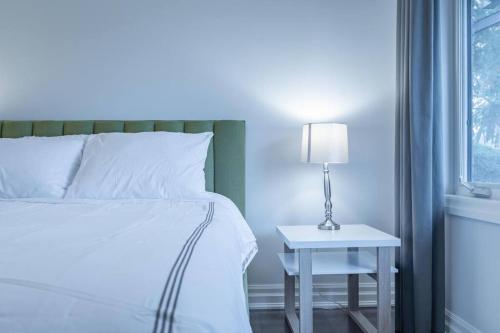 a bedroom with a bed and a table with a lamp at Luxurious & Modern 4BR House w/ 3 Car Parking in Burlington