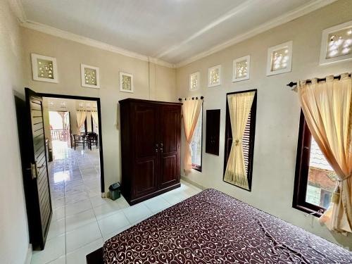a bedroom with a bed and a door and windows at Bidel's House in Gianyar