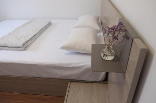 a bed with a vase of flowers on a night stand at Mir Guesthouse in Jeju