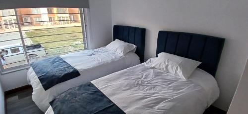 dwa łóżka w pokoju z oknem w obiekcie CasAvella Paipa w mieście Paipa