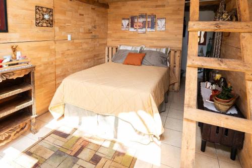 1 dormitorio con 1 cama en una habitación con paredes de madera en Cabaña Colibrí, en Santa Cruz Verapaz