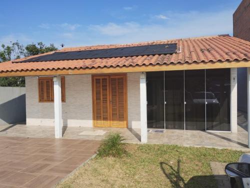 uma casa com painéis solares no telhado em Casa em imbé em Imbé