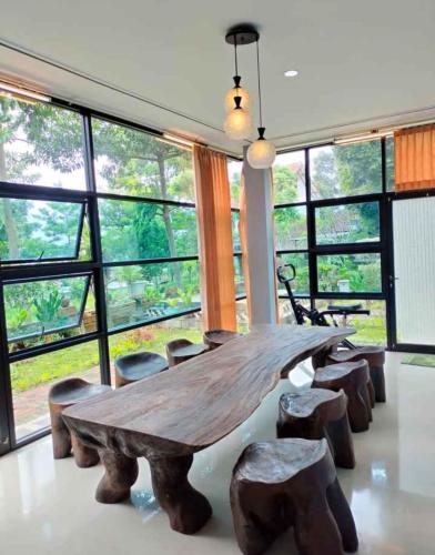 una mesa de madera y algunas sillas en una habitación con ventanas en Villa Omahe Dewe by Da- hee, en Bandungan