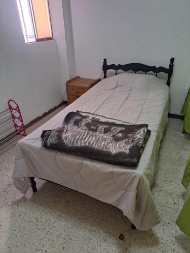 Una cama con una manta en una habitación en Sientete en casa, en Ilo
