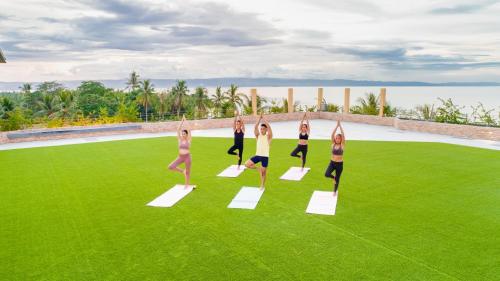 a group of women doing a yoga pose on the grass at Modala Beach Resort in Panglao