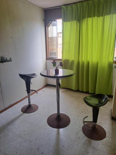 - une table dans une chambre avec un rideau vert dans l'établissement Sientete en casa, à Ilo