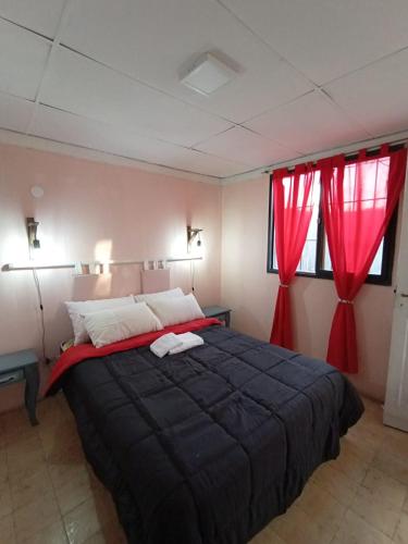 a bedroom with a large bed with red curtains at Alojamiento Carmencita in Guaymallen