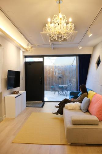 a woman sitting on a couch in a living room at Mir Guesthouse in Jeju