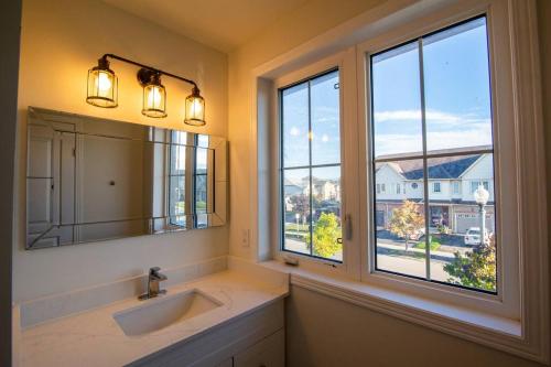 a bathroom with a sink and a mirror and windows at Executive 3 Bedroom townhouse close to the Lake in Hamilton