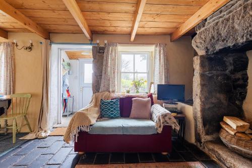 ein Wohnzimmer mit einem Sofa vor einem Kamin in der Unterkunft Kitts Cottage Rural, Woodburner, King Size Bed in Redruth