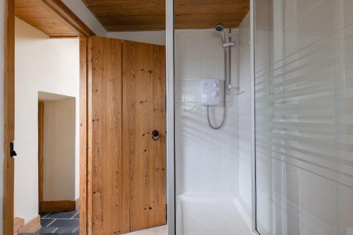 a shower with a glass door in a bathroom at Kitts Cottage Rural, Woodburner, King Size Bed in Redruth