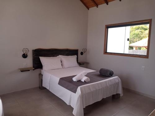 a bedroom with a large white bed with a window at Chalés Vale Sereno in Camanducaia