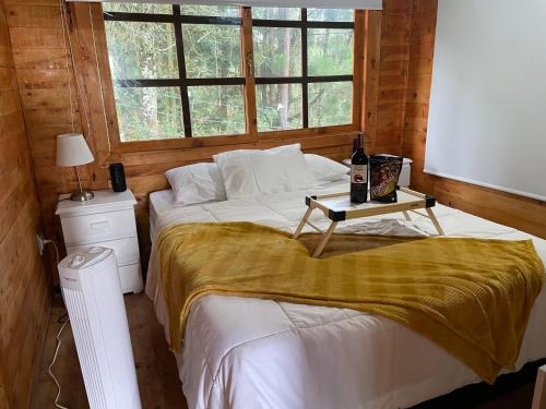 a bedroom with a bed and a table with a bottle of wine at Lovely two bedroom cabin on avocado farm in Marinilla