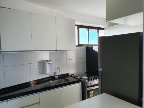 uma cozinha com armários brancos e um frigorífico preto em FLATS ROSARINHO PRINCE SPRING no Recife