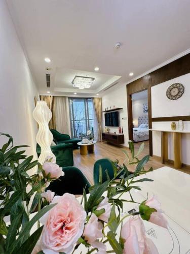 ein Wohnzimmer mit einem Tisch mit rosa Rosen in der Unterkunft LuxurySunlit/2bed/P10Times in Hanoi