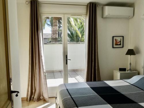une chambre avec un lit et une porte coulissante en verre dans l'établissement Villa 4*** à 20m de la plage, jardin, parking, clim, WIFI - FR-1-728-15, à Cavalaire-sur-Mer