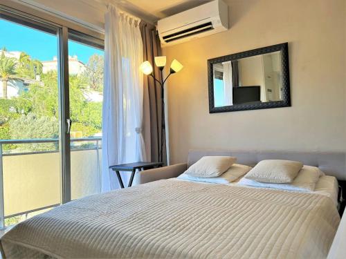 - une chambre avec un lit avec un miroir et un balcon dans l'établissement Studio cosy avec coin nuit, climatisation, animaux admis, centre-ville - 4 pers - FR-1-251-579, au Lavandou