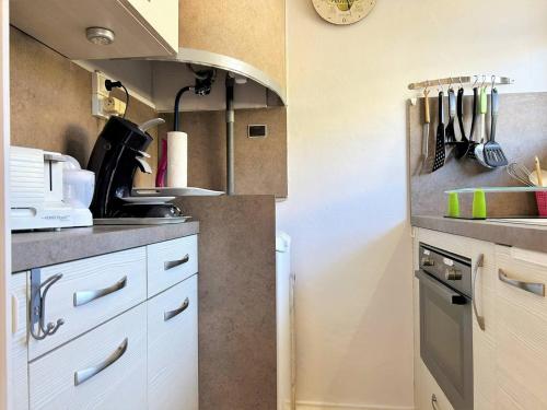 une cuisine avec des armoires blanches et un évier dans l'établissement Studio cosy avec coin nuit, climatisation, animaux admis, centre-ville - 4 pers - FR-1-251-579, au Lavandou