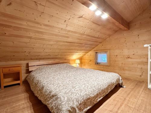 une chambre dans une cabane en rondins avec un lit dans l'établissement Appartement calme près du lac avec jardin, balcon, parking et wifi - FR-1-624-150, à Samoëns