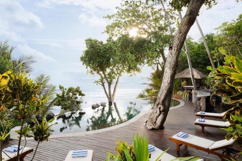 um deque de madeira com cadeiras e vista para o oceano em The Cove Bali by Nakula em Balian