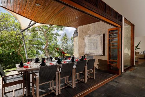 uma sala de jantar com uma mesa longa e cadeiras em The Cove Bali by Nakula em Balian