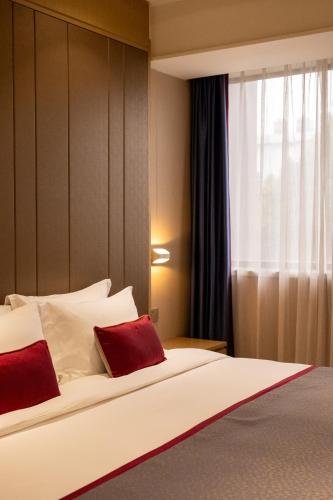 a bedroom with a bed with two red pillows at SHANGHAI-DECO Hotel-Free shuttle bus to Pudong Airport and Disneyland in Shanghai