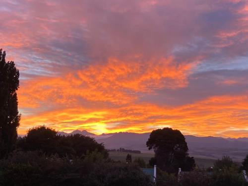 a sunset with trees and mountains in the background at The Gables-Clarens in Clarens