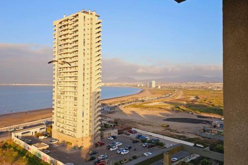 a tall white building next to a beach at Departamento en Costanera Coquimbo in Coquimbo