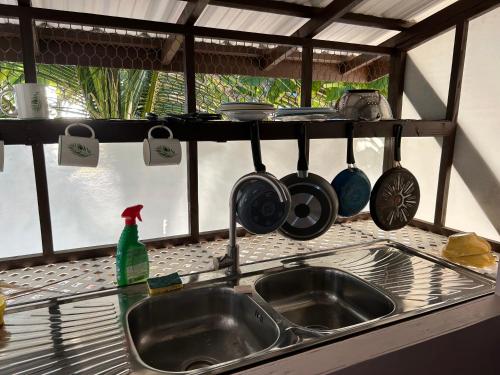 - un évier de cuisine avec des casseroles et des poêles suspendues au-dessus dans l'établissement Rangiroa Bliss, à Tiputa