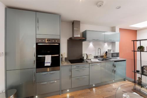 a kitchen with stainless steel appliances and orange walls at City Chic: Elegant Flat in a Prime Location in London