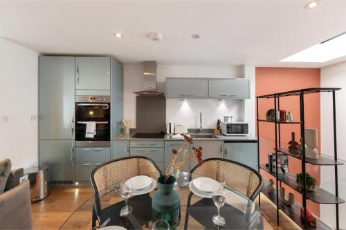 a kitchen with a table and two chairs and a kitchen with a stove at City Chic: Elegant Flat in a Prime Location in London