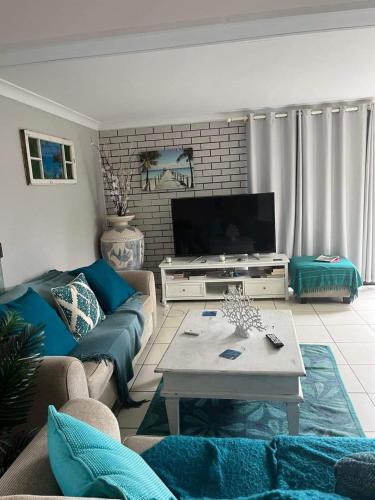 a living room with a couch and a tv at Whalehouse in Bongaree