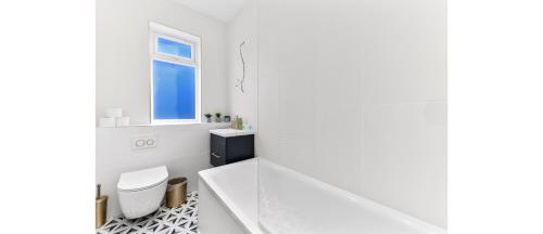 een witte badkamer met een toilet en een raam bij Serene, Stylish, Spacious Brand New for 2023! in Londen